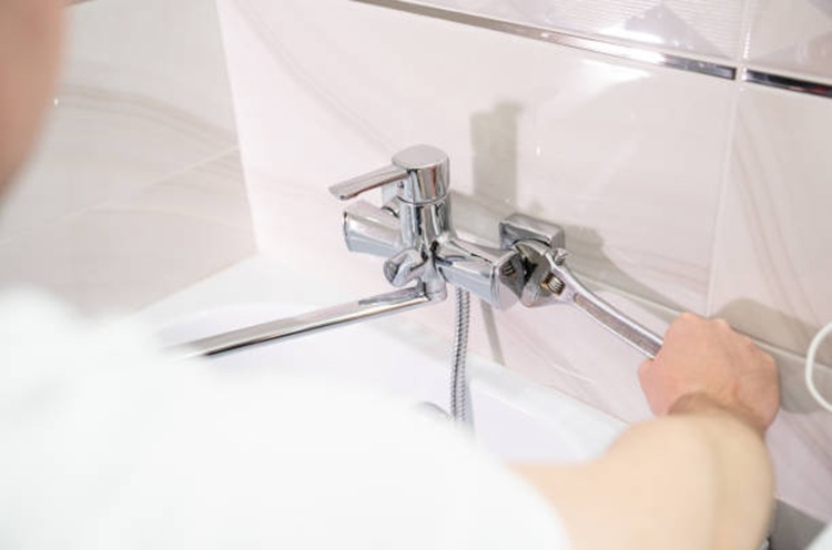 Technician fixing a bathtub valve with a wrench tool