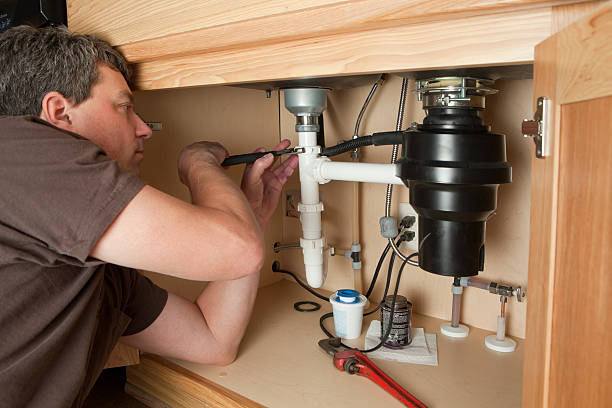 A professional plumber installing a garbage disposal in a kitchen