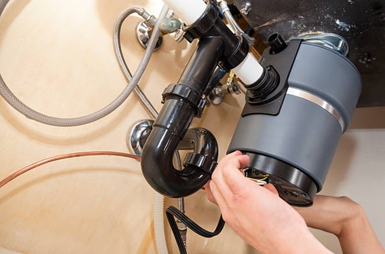Technician connecting plumbing to a new garbage disposal system