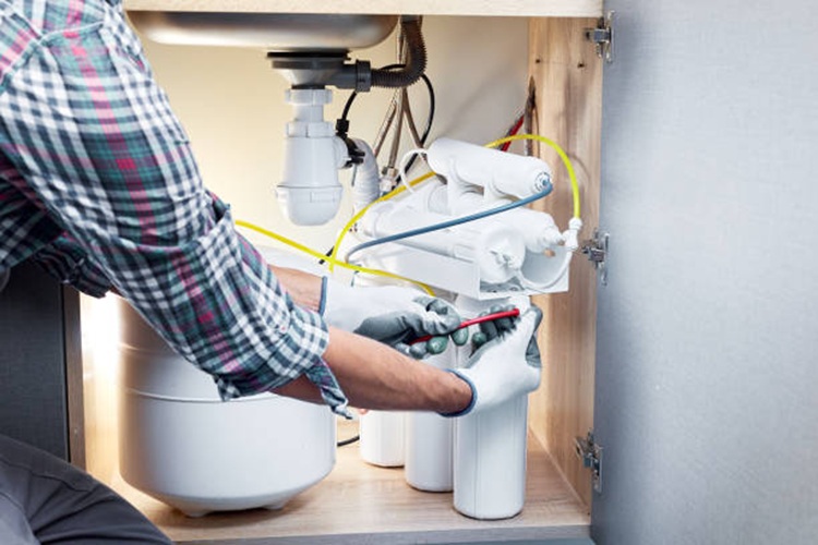Contractor installing reverse osmosis water filter under kitchen sink