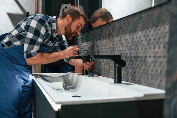 Technician installing modern black faucet on stylish bathroom sink