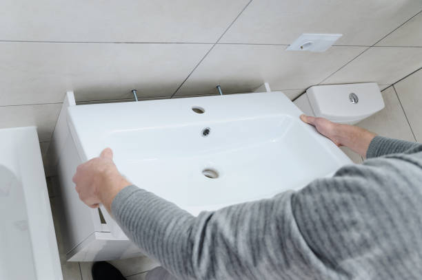 Professional installing a new bathroom sink in a tiled bathroom space