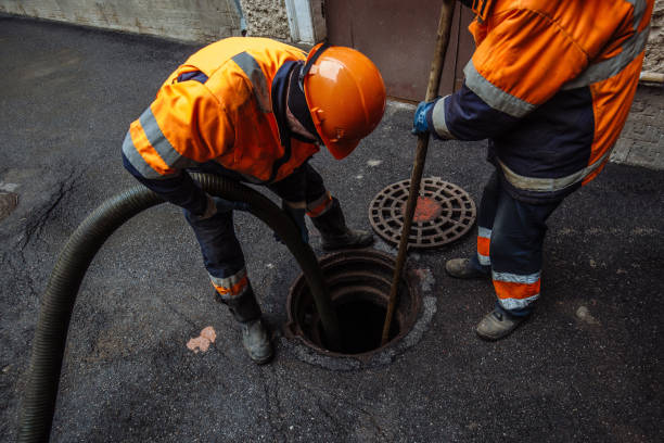Skilled workers removing debris from sewer line through manhole